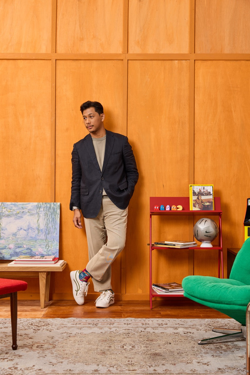 Man leaning against a wooden wall with a colorful interior setting